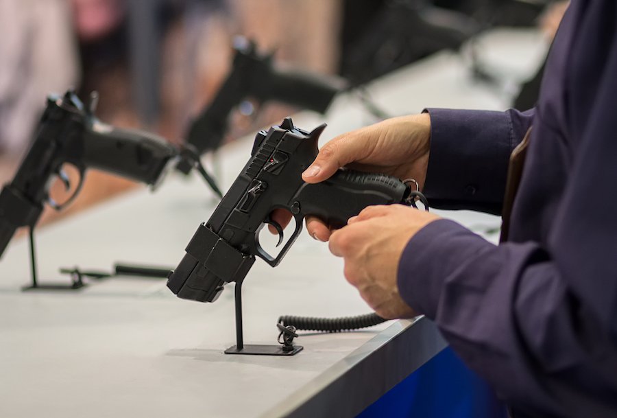 Primer plano de un hombre sosteniendo un arma en una tienda de armas