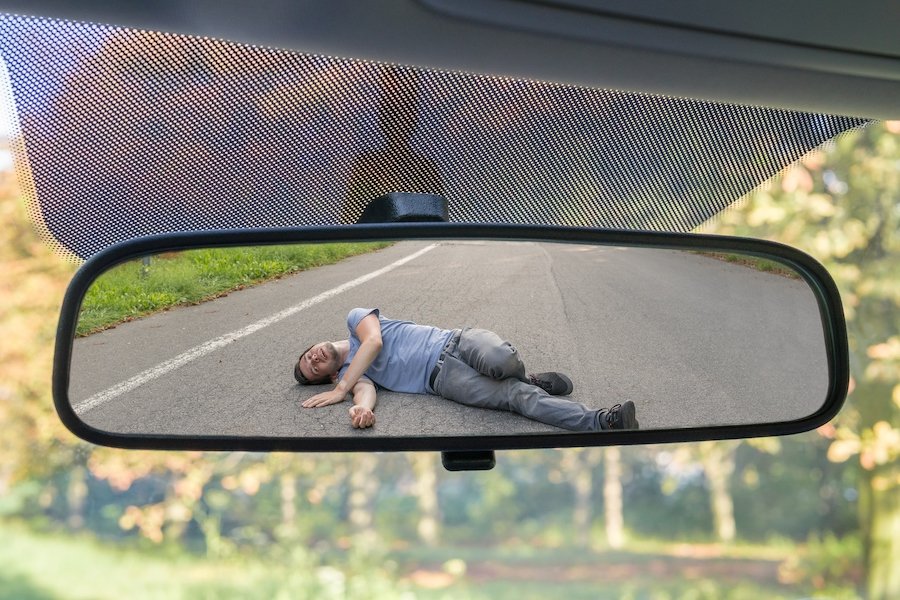 Pedestrian on road after being hit by car, as seen through its rear-view mirror - Las Vegas Nevada hit and run laws make it a felony to flee the scene of an accident where a victim is injured