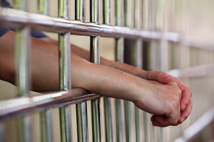 Hands reaching through jail cell