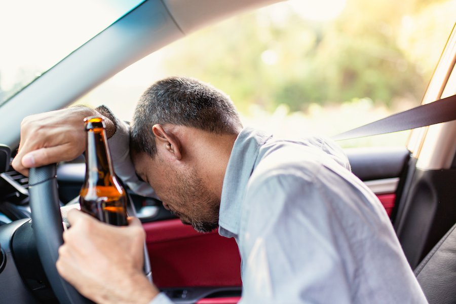 Man passed out drunk over steering wheel and holding beer
