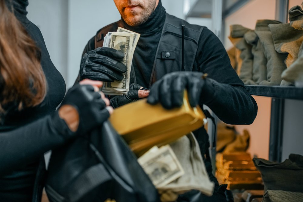 Bank robbers stuffing money into their bag - Penal Code 213 PC sets forth the penalties for robbery in California.
