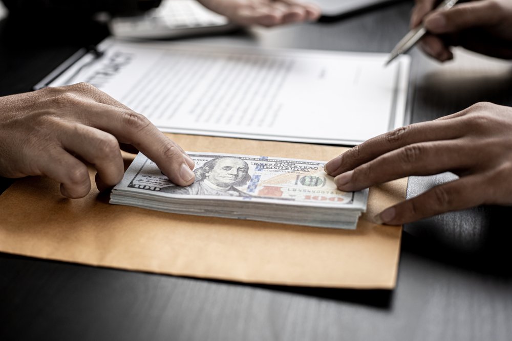 Person sliding money across a desk to someone else.
