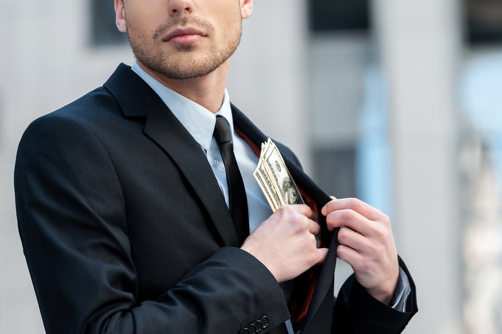 Un hombre metiendo dinero en su bolsillo de la chaqueta.