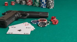Poker chips, cards and gun on a poker table background.