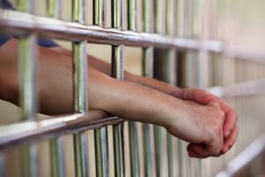 Hands sticking through jail bars