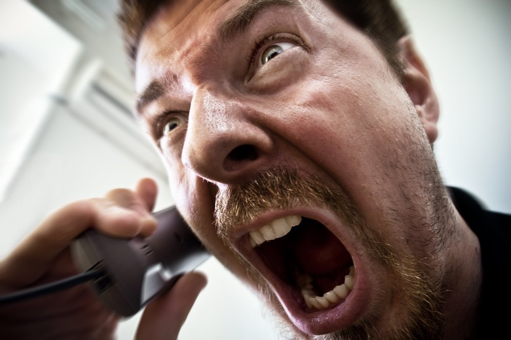 Hombre gritando mientras está en el teléfono.
