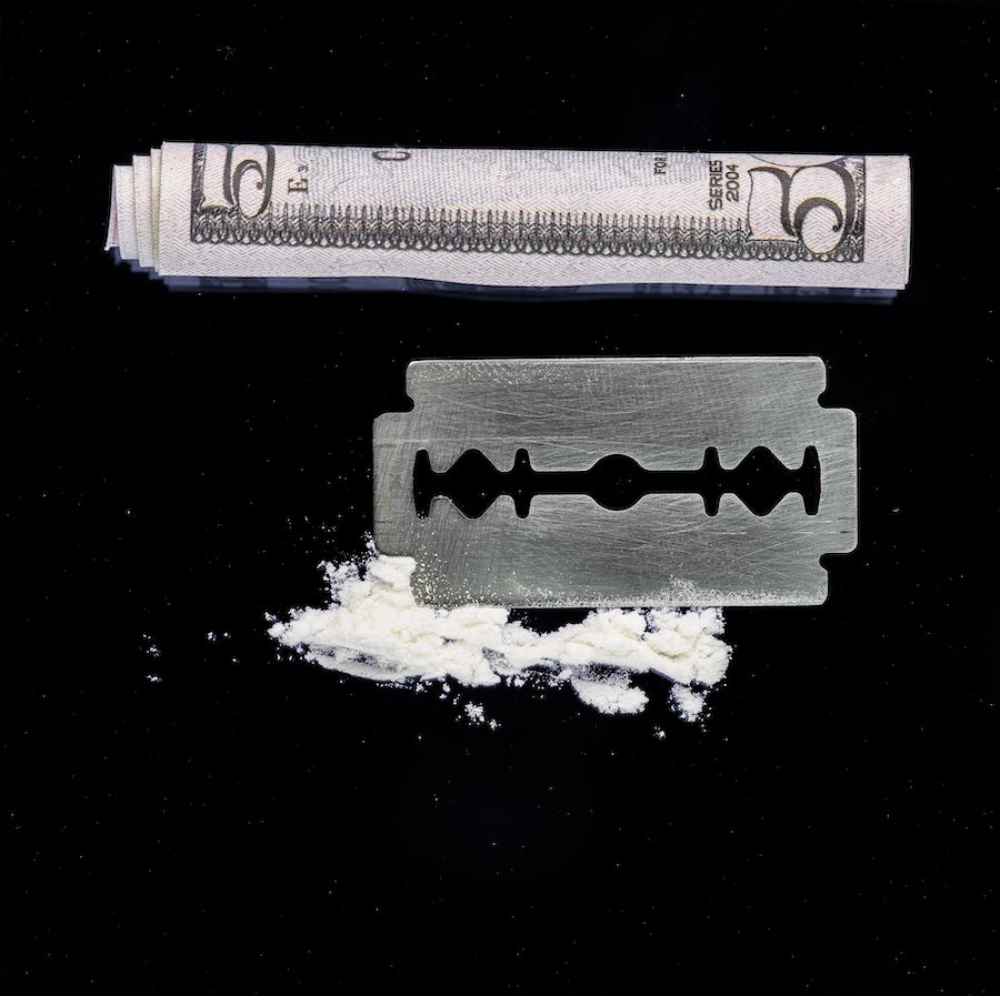 elementos de drogas que consisten en una navaja y un billete de cinco dólares enrollado cerca de cocaína