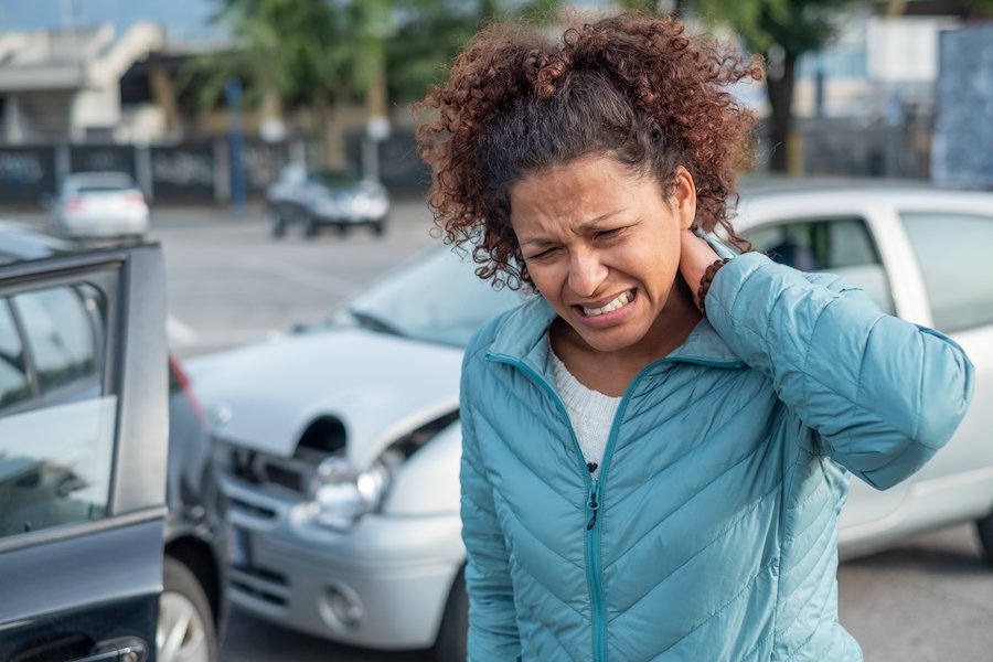 Víctima de accidente automovilístico sosteniendo el cuello después de un accidente automovilístico por colisión trasera, y ella podría demandar a la parte responsable por sus lesiones