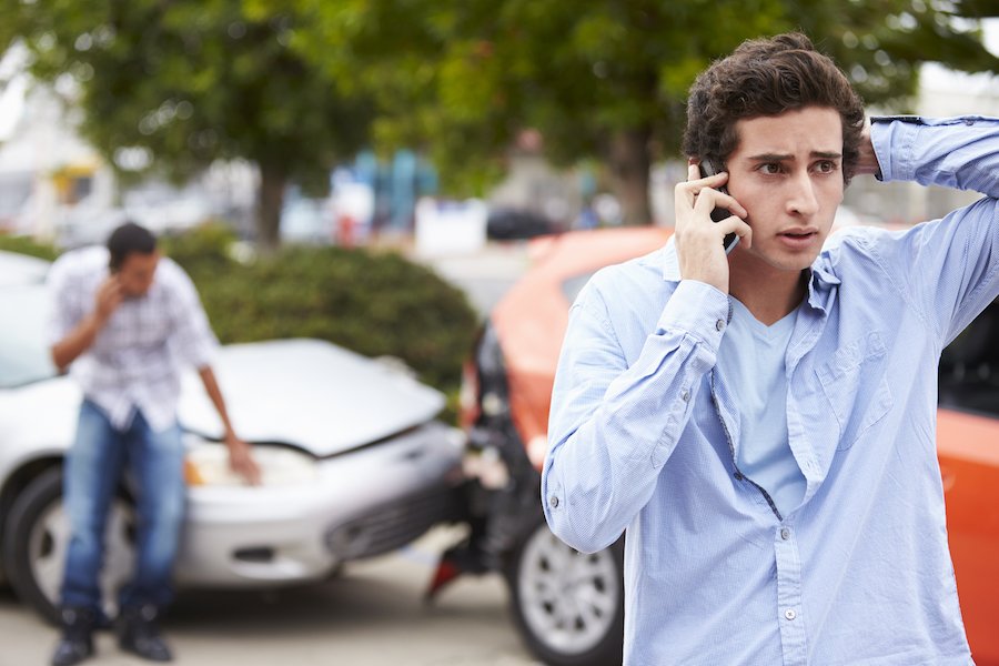 Aftermath of fender bender, with both drivers speaking on cell phones