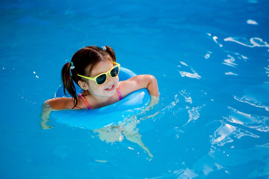 niño en dispositivo de flotación en piscina