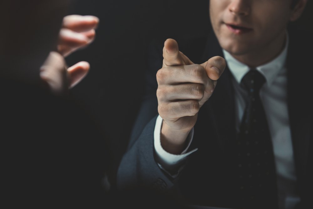 A man in a suit pointing his finger at someone.