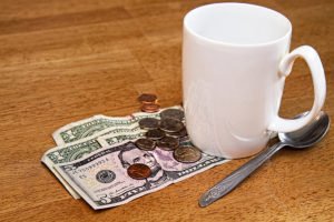 Taza de café, cuchara y propina en efectivo en una mesa