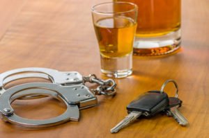 Alcoholic drinks, keys, and handcuffs on a table.