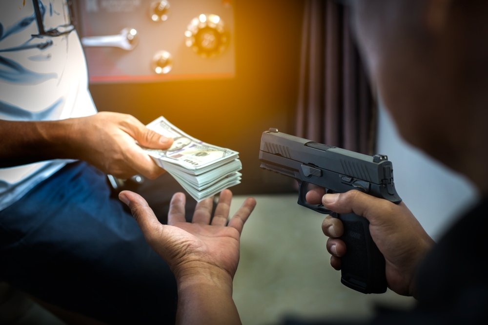 Robber pointing gun and taking money from a victim - a crime that would invoke firearms sentencing enhancements in California