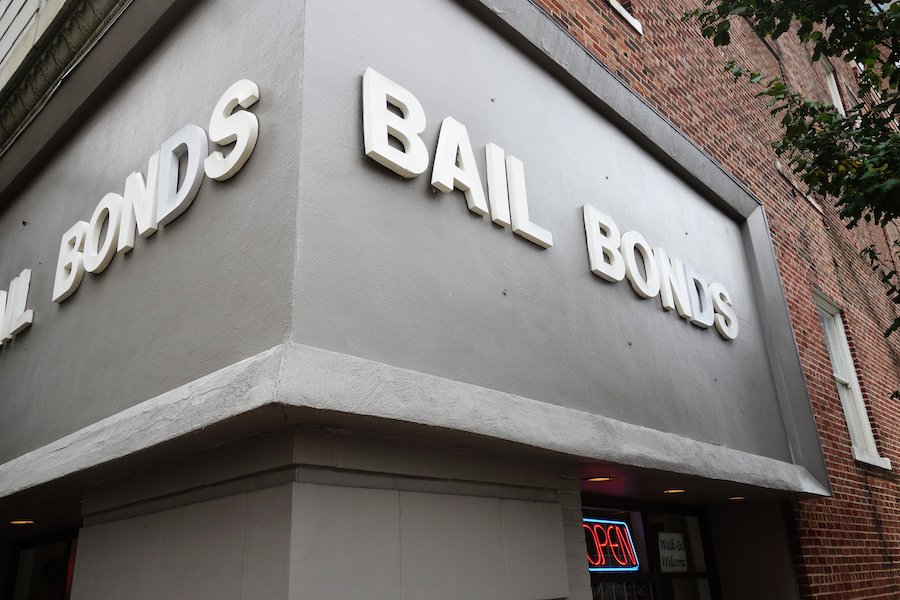 Grey exterior of a bail bonds storefront on a street corner