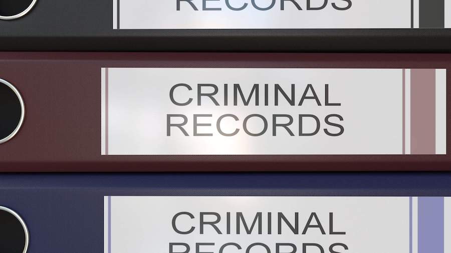 Vertical stack of multicolor office binders with Criminal records tags