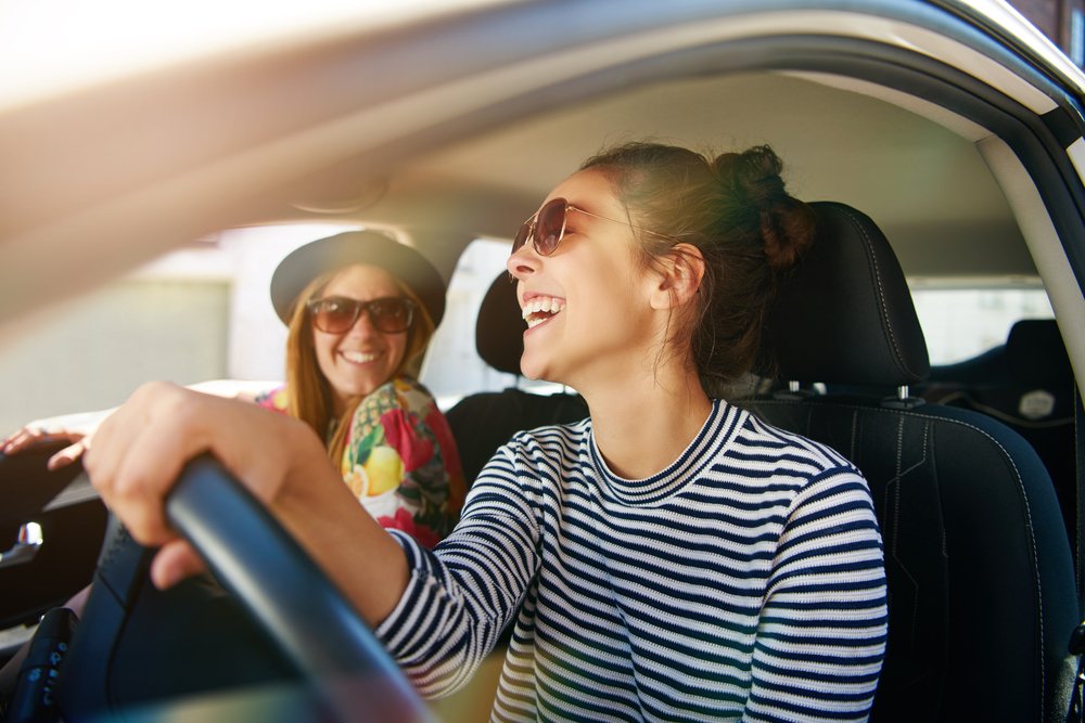 A driver and passenger laughing in a car.