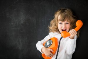 A child yelling into a phone - prank calling is illegal in many states