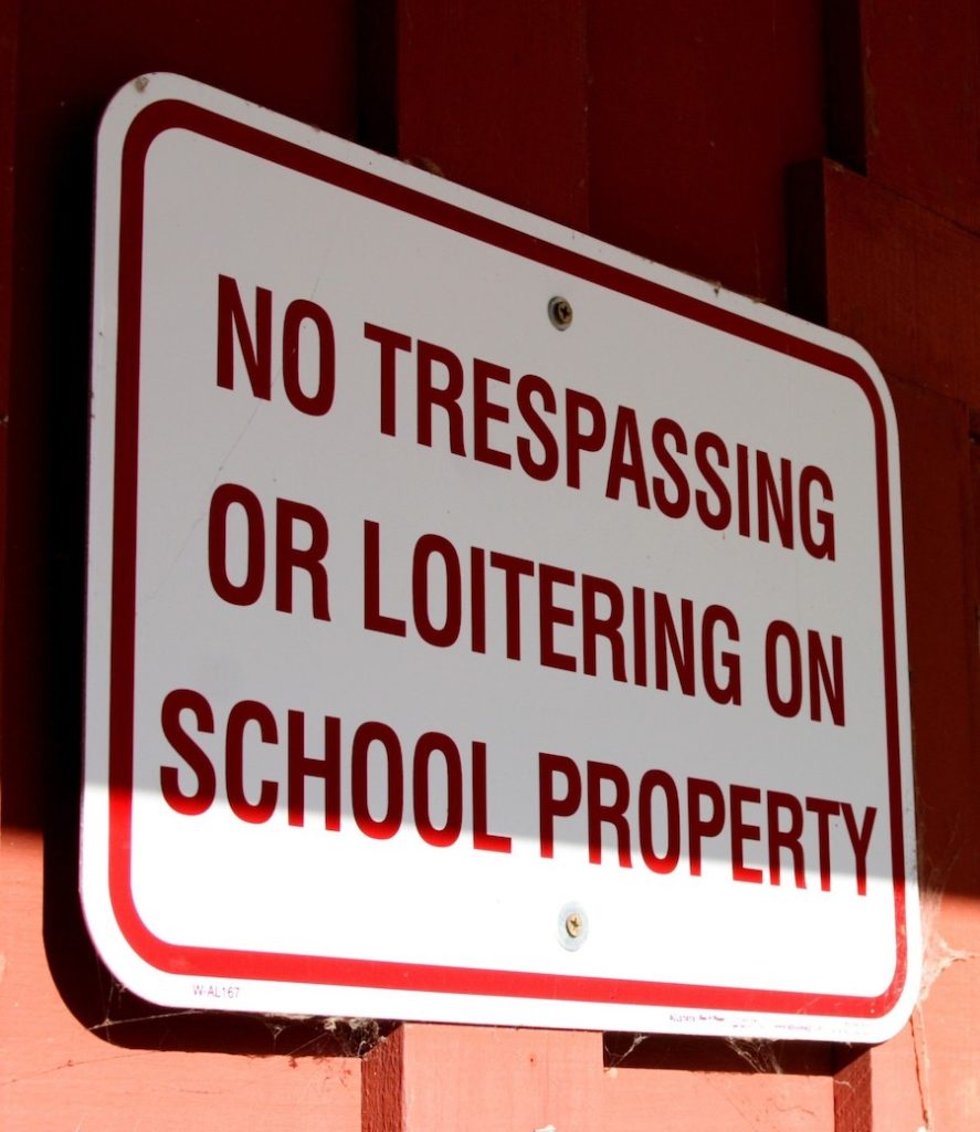 Señal que dice "No entrar o merodear en la propiedad de la escuela"