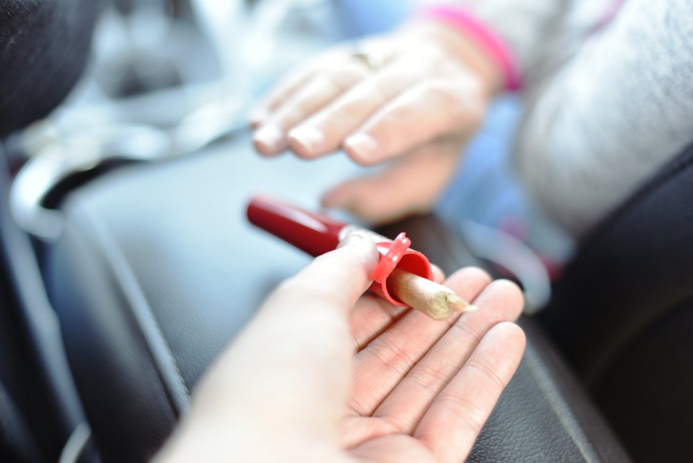 Motorist holding a joint of marijuana as an example of a Vehicle Code 23222 CVC open container violation