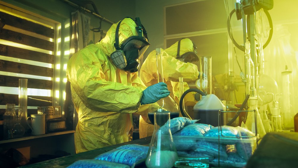 Dos personas con equipo de protección en un laboratorio de metanfetamina como ejemplo de una violación del Código de Salud y Seguridad 11383.5 HS