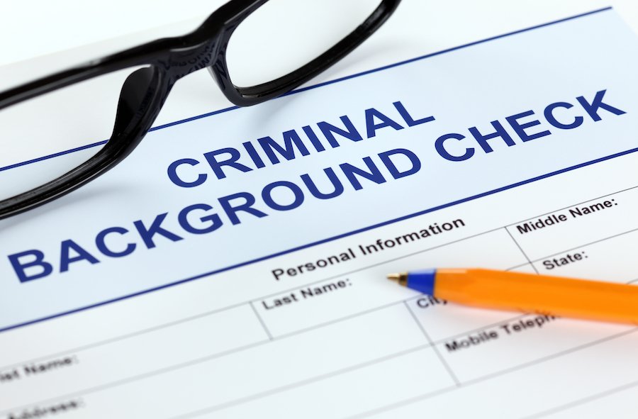Formulario de solicitud de verificación de antecedentes penales con gafas y bolígrafo.
