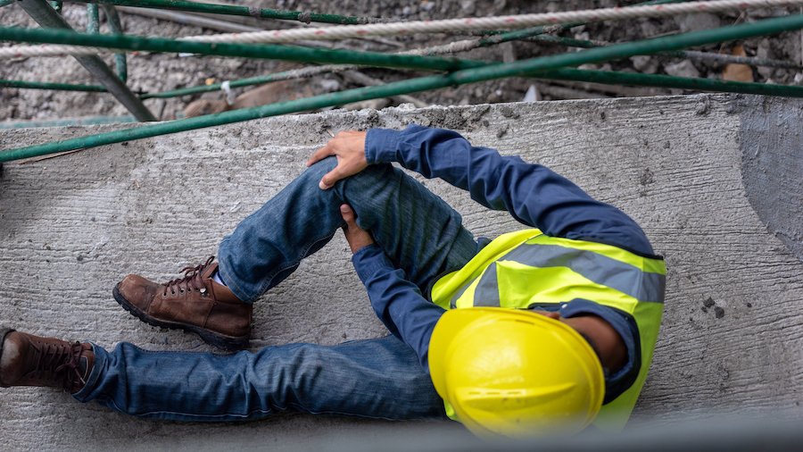 Knee accident at work of construction worker at site. Builder accident falls scaffolding on floor.