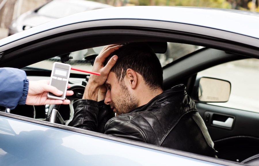 Conductor detenido por DUI, y el policía está administrando un alcoholemia en la carretera