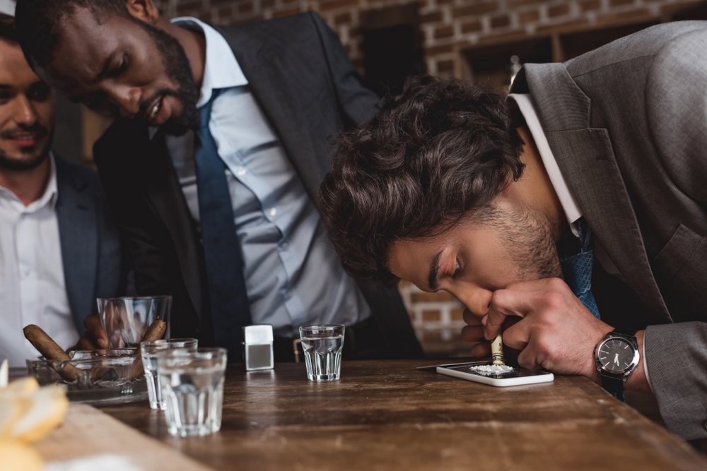 Un hombre haciendo una línea de cocaína en una fiesta.