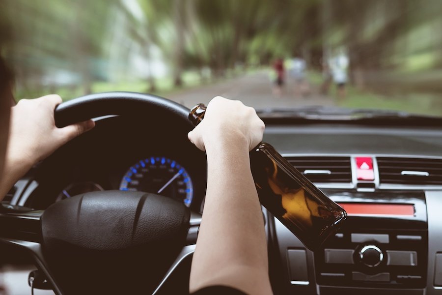 Woman drinking beer while driving a car