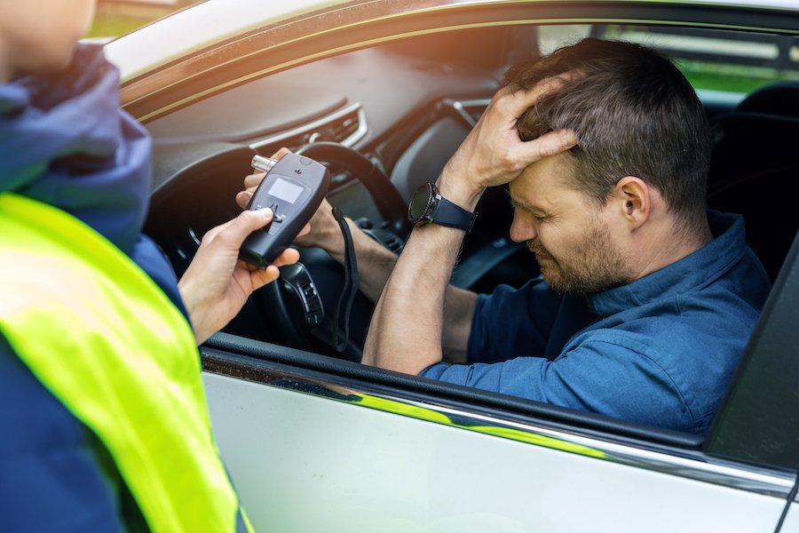 Police administering roadside breathalyzer to DUI suspect in car