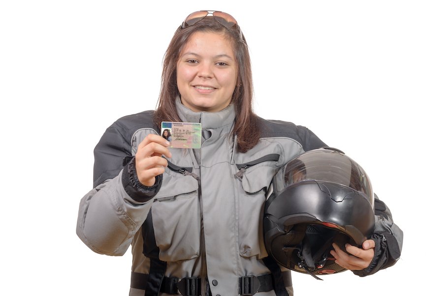 Mujer joven feliz mostrando orgullosa su nueva licencia de motocicleta