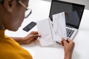 Person pulling a paycheck out of an envelope.