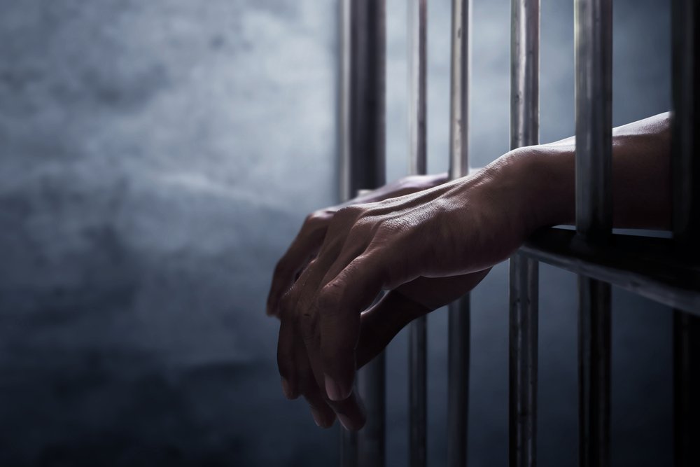 Inmate's hands extending out of a jail cell