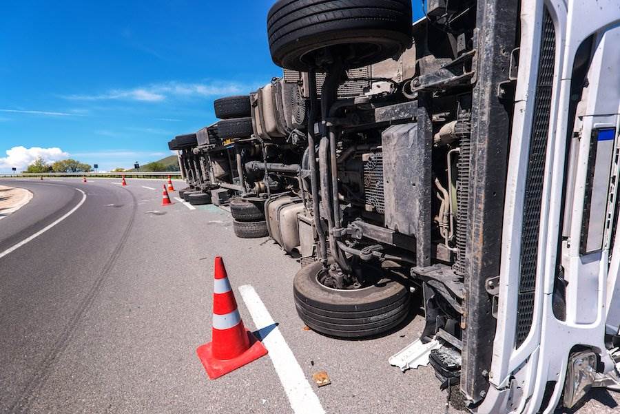 Overturned truck on highway with traffic cones
