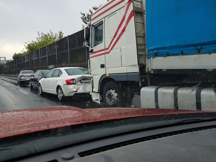 Aftermath of truck rear-rending car on road