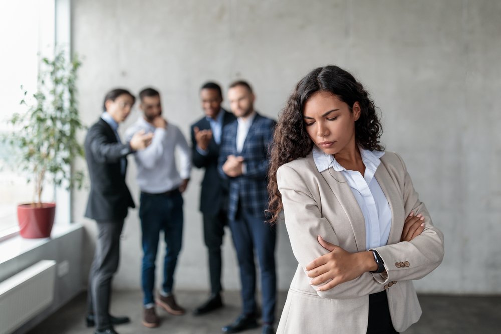 A female employee being laughed at by male colleagues.