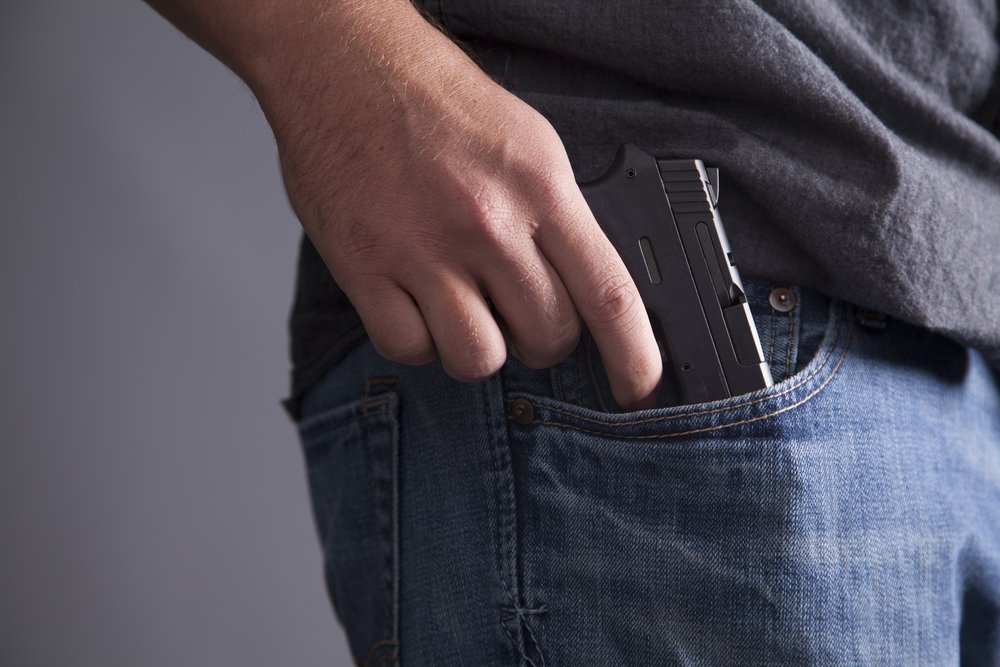 Un hombre sacando una pistola de su bolsillo delantero