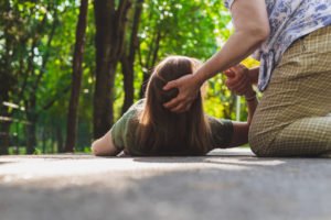 Woman having her head held up after fainting.