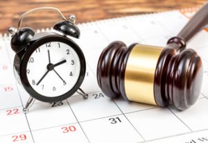 Gavel and a clock resting on a calendar.