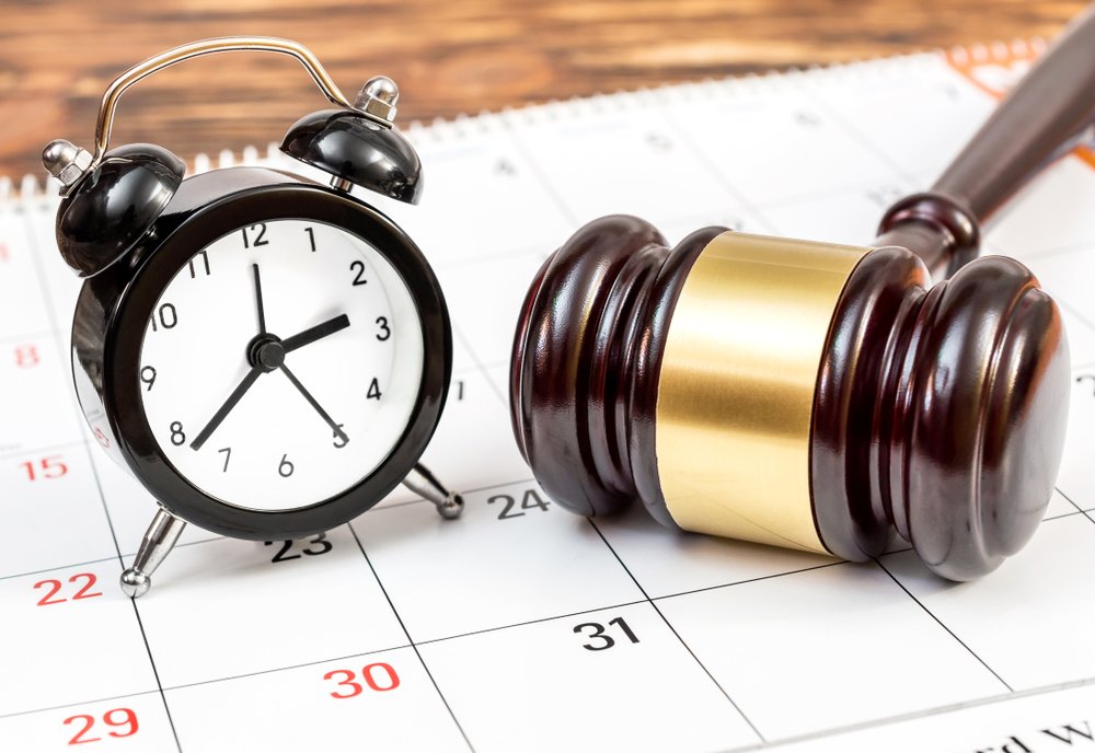 Gavel and a clock resting on a calendar.