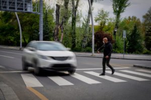 Persona caminando hacia la acera con un coche que viene