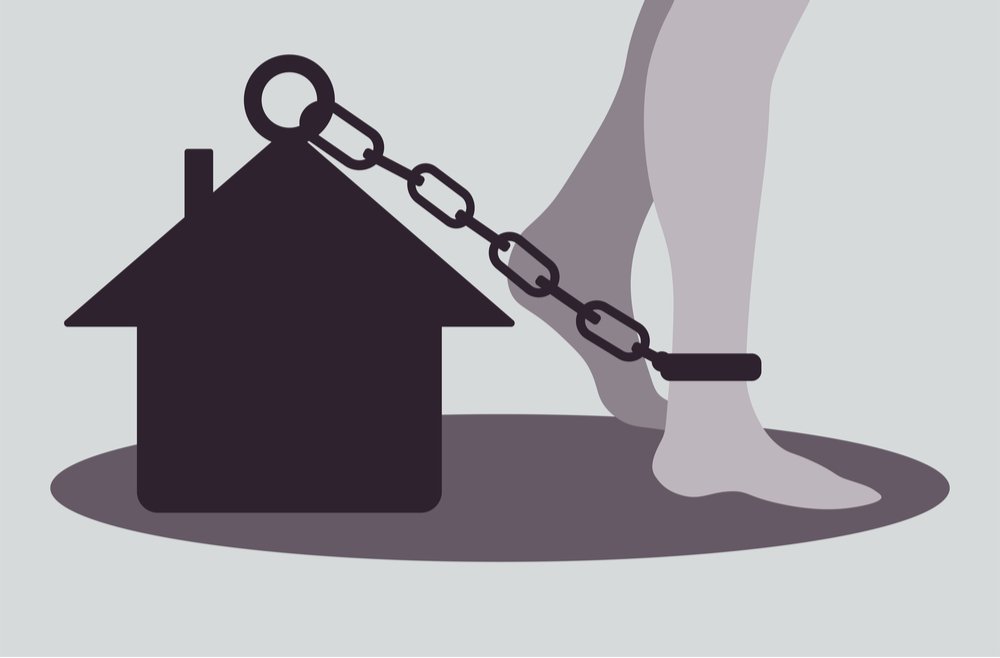 Una ilustración de un tobillo encadenado a una casa para ilustrar el arresto domiciliario en California