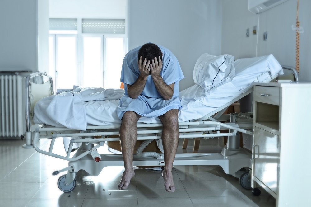 Paciente sentado en la cama del hospital - los daños por dolor y sufrimiento tienen como objetivo compensar a las víctimas por el dolor físico y el angustia mental
