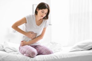 Woman on bed holding her abdomen in pain