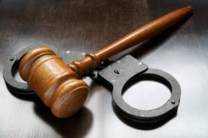 Gavel and handcuffs on wooden background