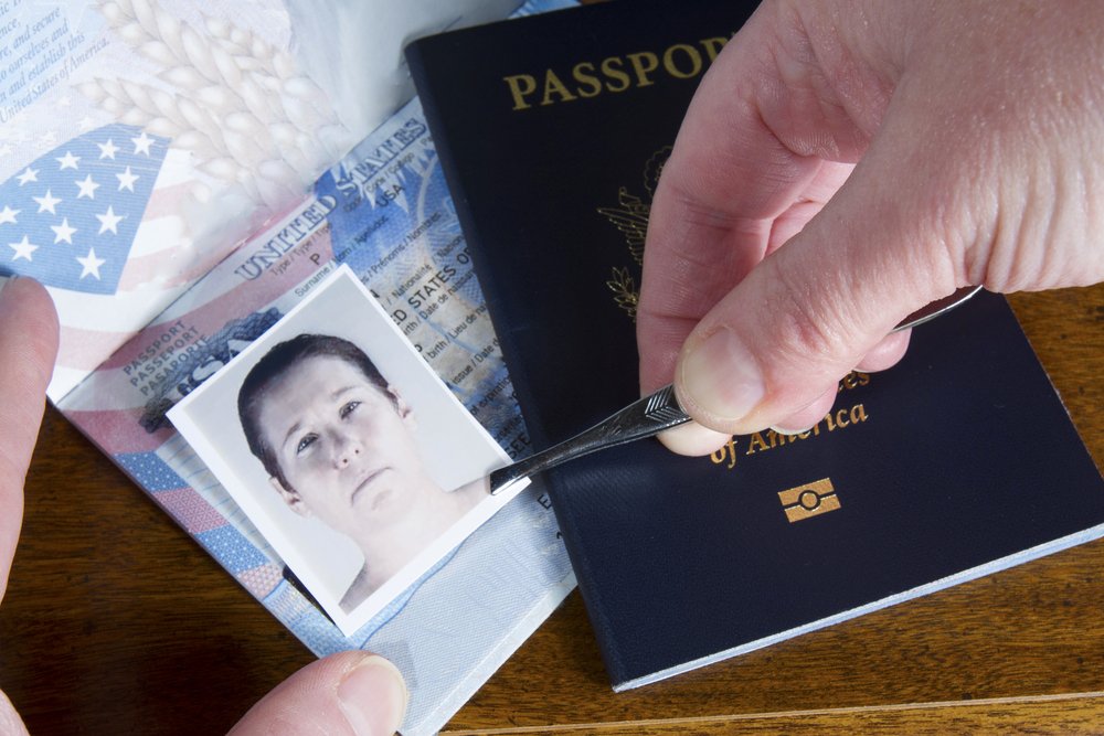 Person using tweezers to switch out a passport photo.