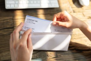 Person opening up an envelope containing a paycheck.