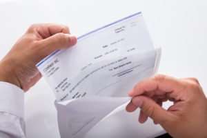 hands opening an envelope with a paycheck with workers' comp benefits