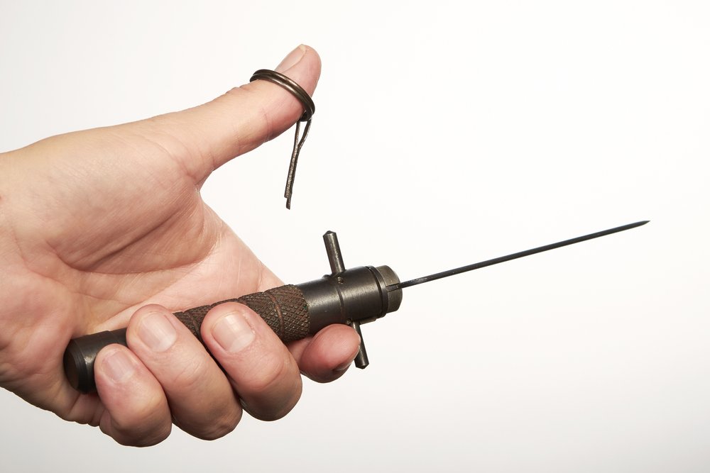 Primer plano de una mano sosteniendo un cuchillo balístico sobre un fondo blanco